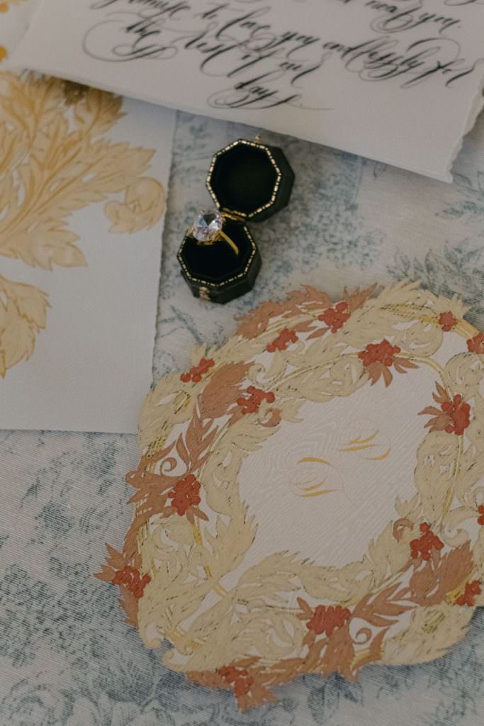 Parisian wedding invite design with a pale gold and pink crest statement piece