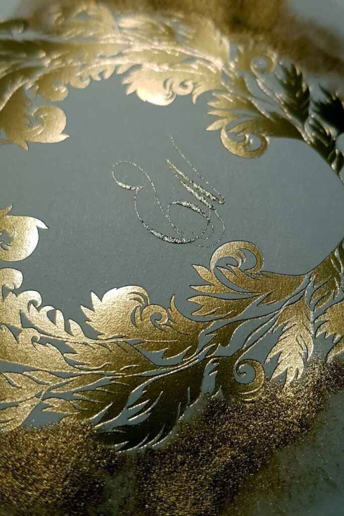 Hand painted gold accents surrounding a classical ornate crest design with calligraphy handwritten initials for a luxury wedding envelope design