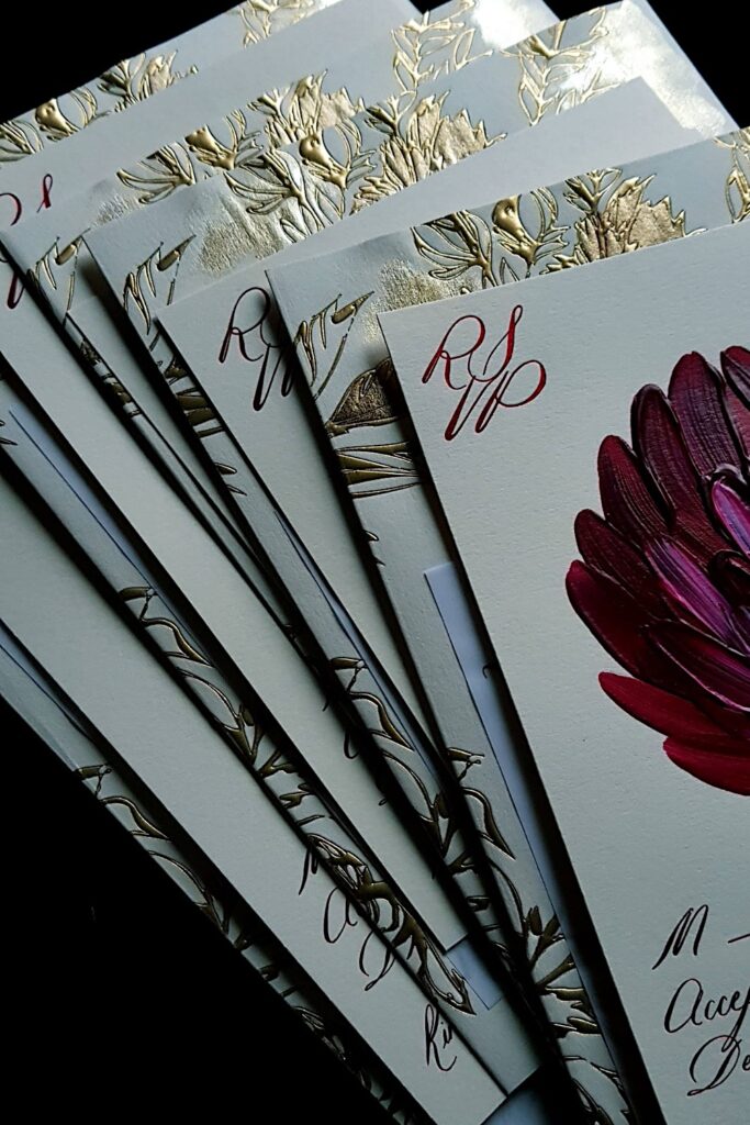 Red hand painted floral rsvp card on a cream card paired with a luxury gold embossed envelope 